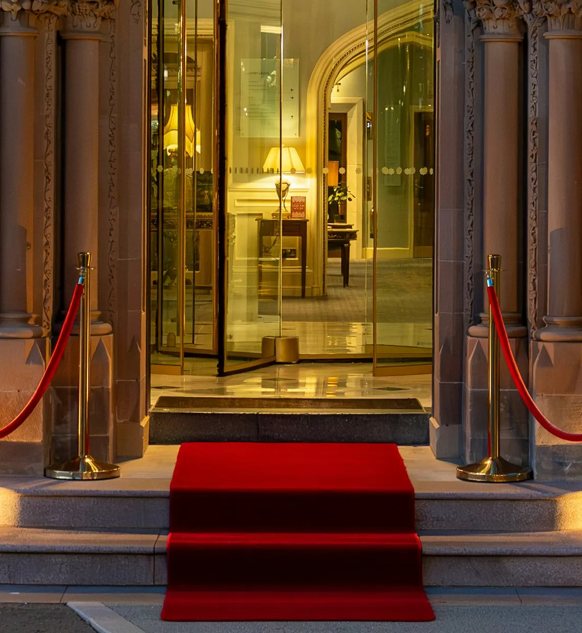 A lit entrance with gold posts and red ropes